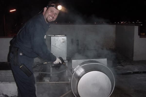 Technician expertly cleans a restaurant kitchen exhaust fan on the rooftop