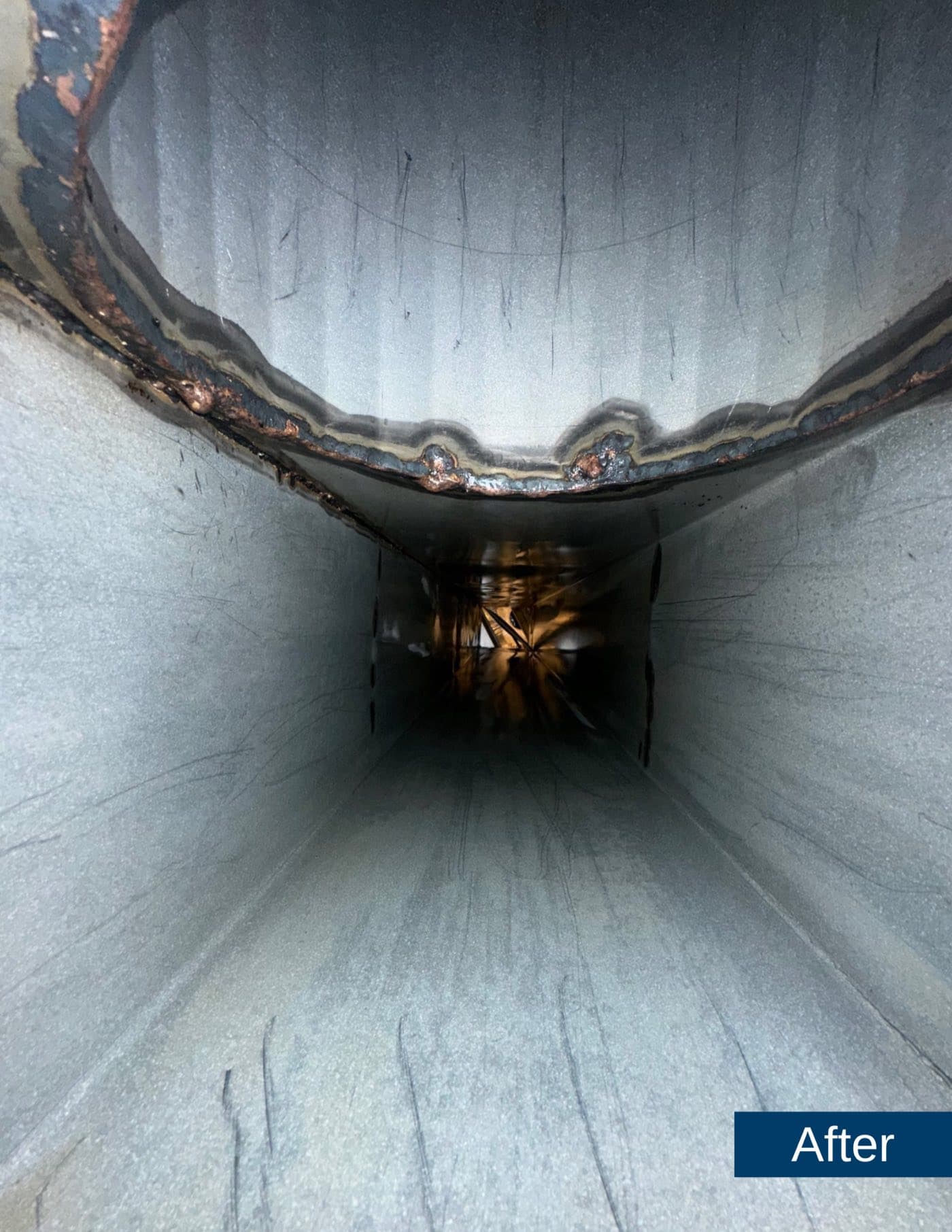 After: the same grease duct cleaned to bare, bright steel