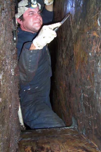 Bryan technician hand-scraping grease deep inside an exhaust duct