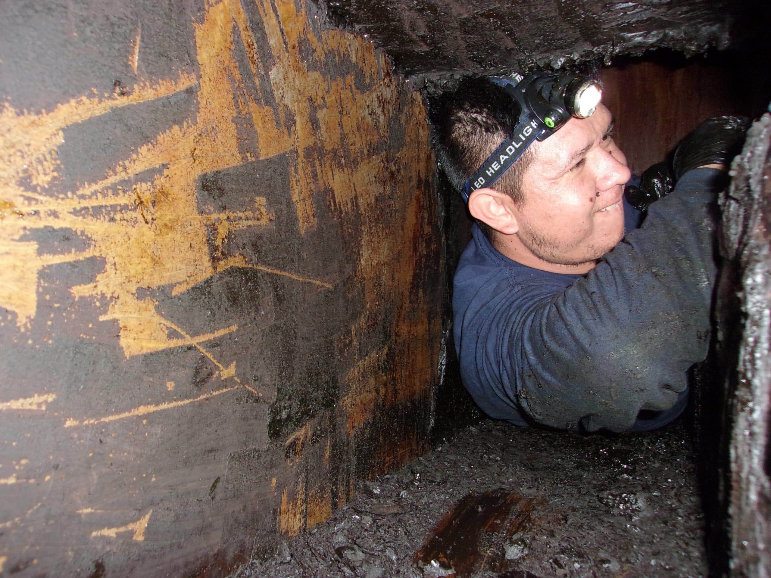 Bryan Exhaust technician working by headlamp inside a grease duct
